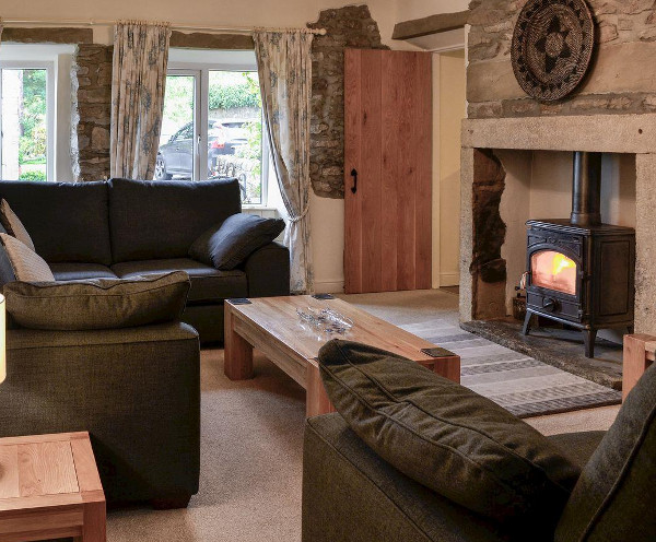 Living room with a wood burning stove at Inglenook Cottage